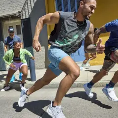 Grupa ludzi w sportowych strojach bierze udział w marszobiegu ulicą.