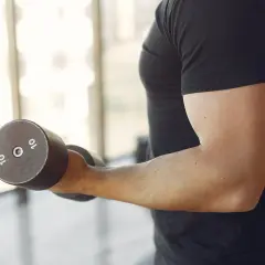 Mężczyzna ćwiczy biceps z hantlem 10 kg. Zastanawiasz się, ile serii na biceps w tygodniu jest optymalne?