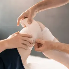 Lekarz opatruje kolano pacjenta z naderwanymi więzadłami. Leczenie może trwać kilka tygodni.
