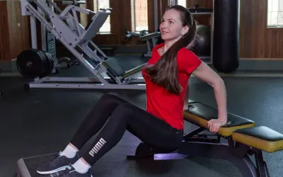 Kobieta wykonuje pompki na triceps na ławce w siłowni.
