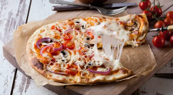 Rozciągający się ser z pizzy 32 cm z pomidorkami i cebulą. Zastanawiasz się, ile kcal ma pizza 32 cm?