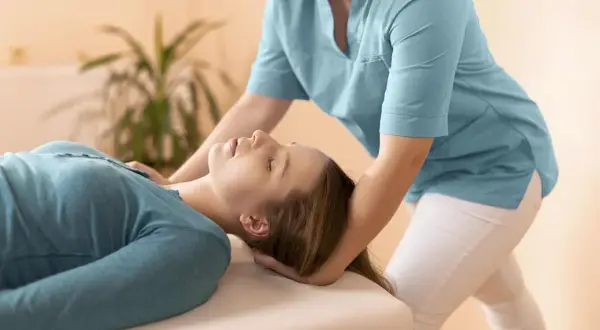 Fizjoterapeuta delikatnie masuje mięsień mostkowy pacjentki, przynosząc ulgę i relaks.