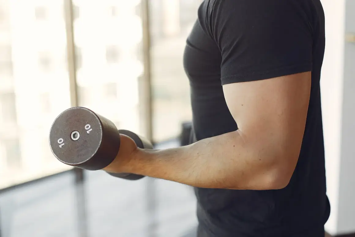 Mężczyzna ćwiczy biceps z hantlem 10 kg. Zastanawiasz się, ile serii na biceps w tygodniu jest optymalne?