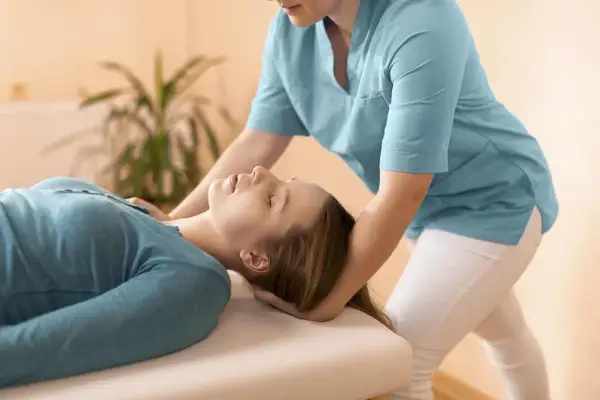 Fizjoterapeuta delikatnie masuje mięsień mostkowy pacjentki, przynosząc ulgę i relaks.